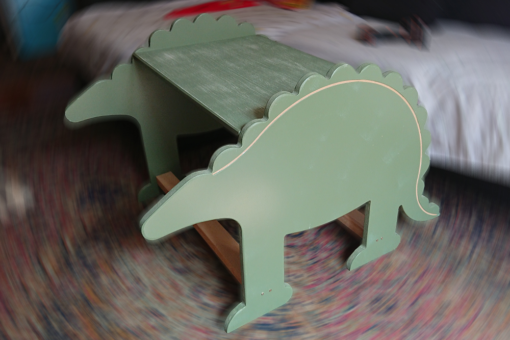 Mesa infantil verde con silueta de dinosaurio.