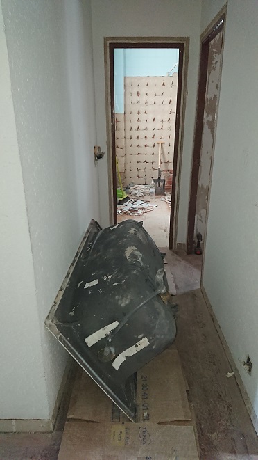 Bañera retirada y apoyada de canto entre restos de demolición.
