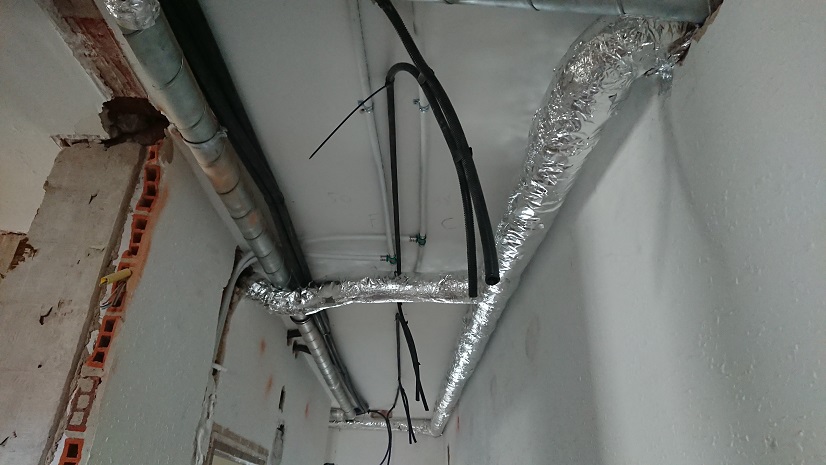 Conductos de ventilación aislados recorriendo el techo del pasillo sin cerrar.