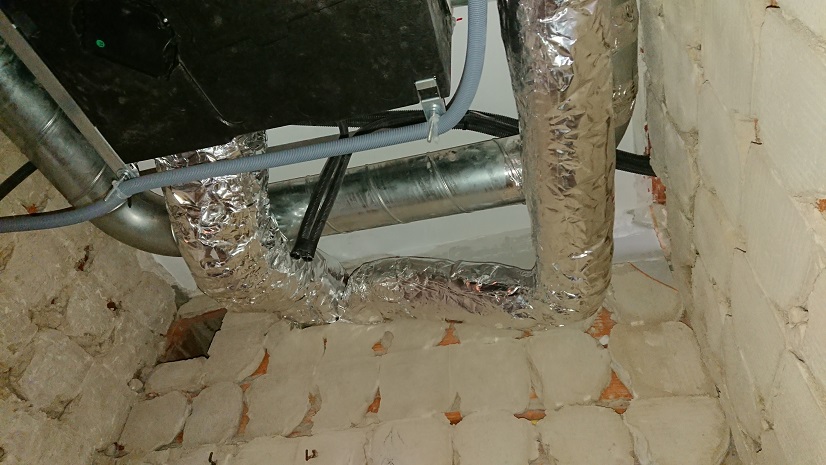 Parte inferior del recuperador de ventilación y conexiones de conductos en el aseo.