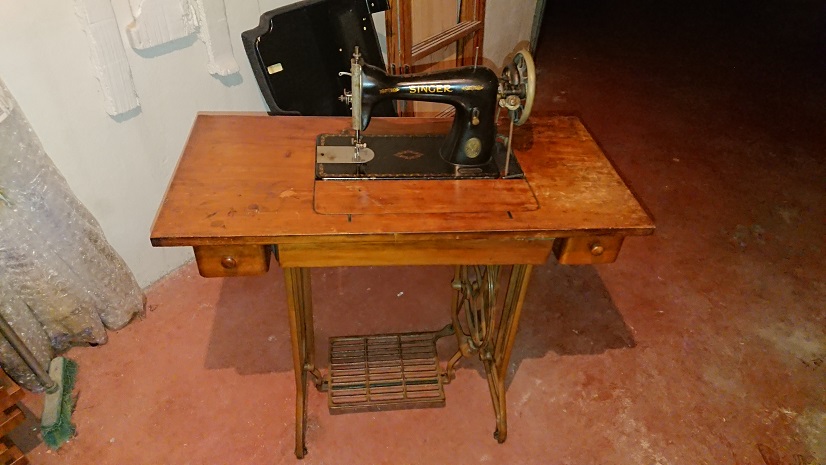 Máquina de coser antigua Singer con tablero y base metálica.