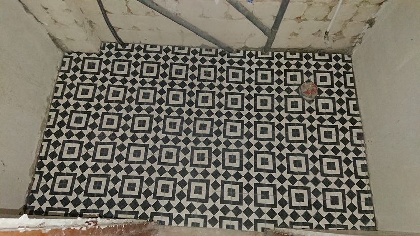 Suelo del aseo con baldosas hidráulicas de dibujo geométrico negro y blanco.