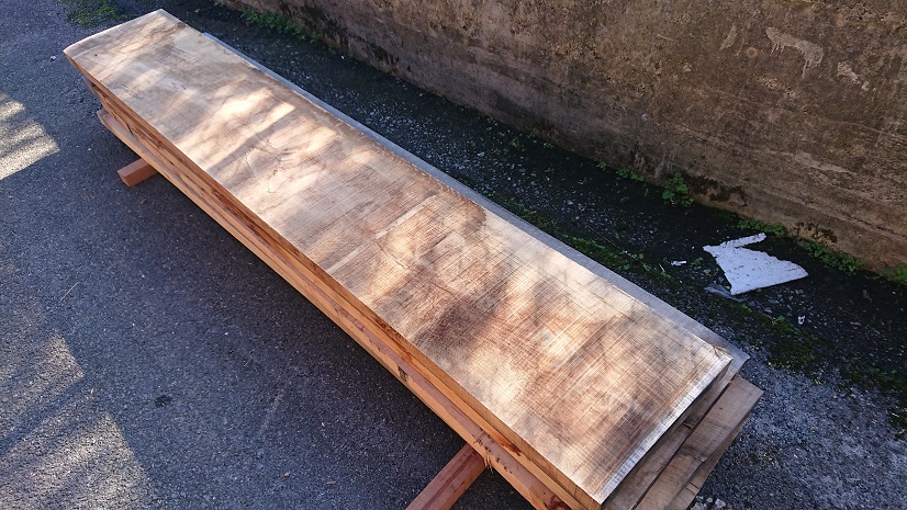 Tablones de madera apilados al aire libre sobre apoyos.