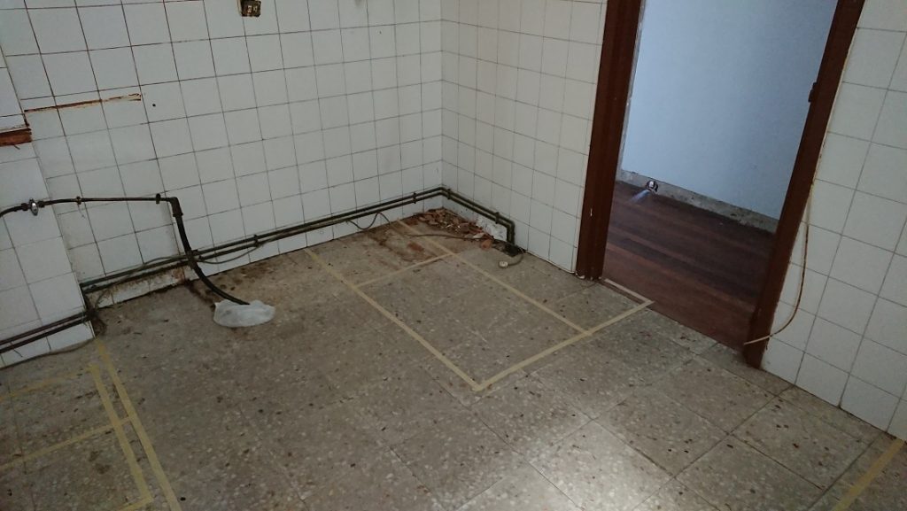Suelo de la cocina vaciada con líneas de cinta marcando las posiciones del mobiliario.