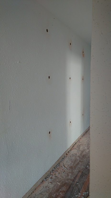 Pared bajo una ventana con orificios y la manguera utilizada durante el insuflado.