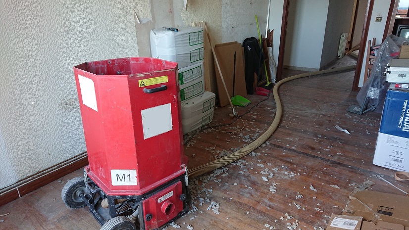 Máquina roja para insuflado de aislamiento con una manguera conectada.