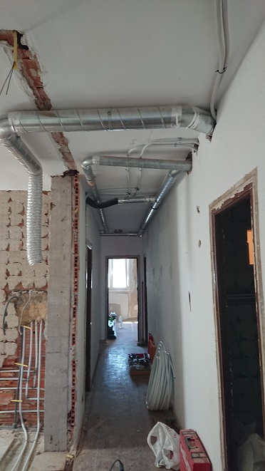 Conductos de ventilación sobre el pasillo, con las paredes y el techo todavía en obras.